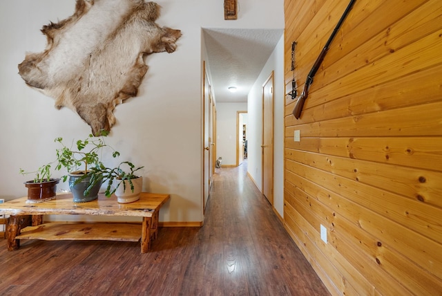 hallway with wood-type flooring, baseboards, and wood walls