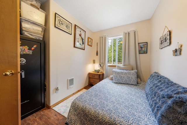 bedroom featuring dark wood finished floors, heating unit, and baseboards