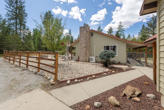 view of home's exterior with a gate, fence, a chimney, a carport, and ac unit