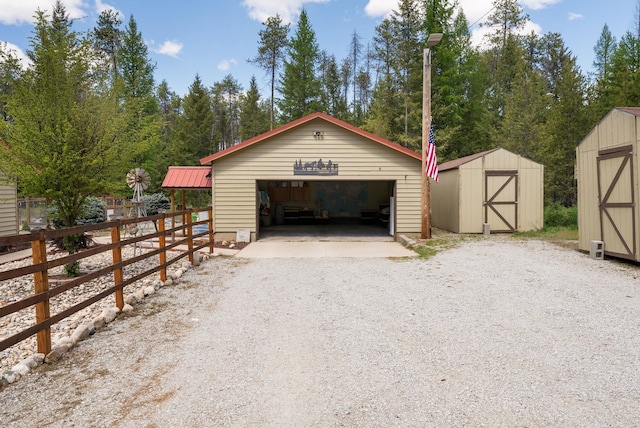 detached garage featuring a storage shed and fence
