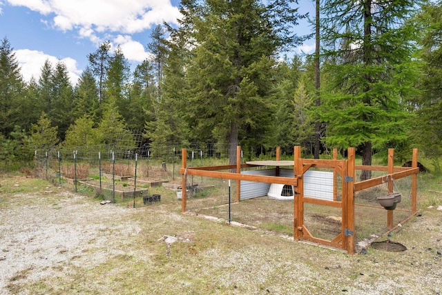 view of yard with a vegetable garden, fence, and a forest view