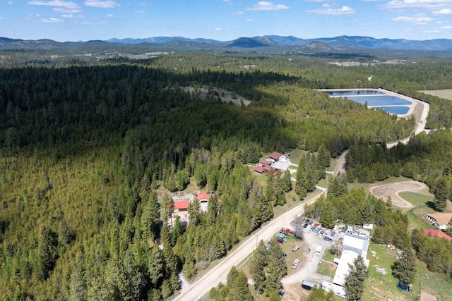 aerial view of property and surrounding area featuring a heavily wooded area and a mountainous background
