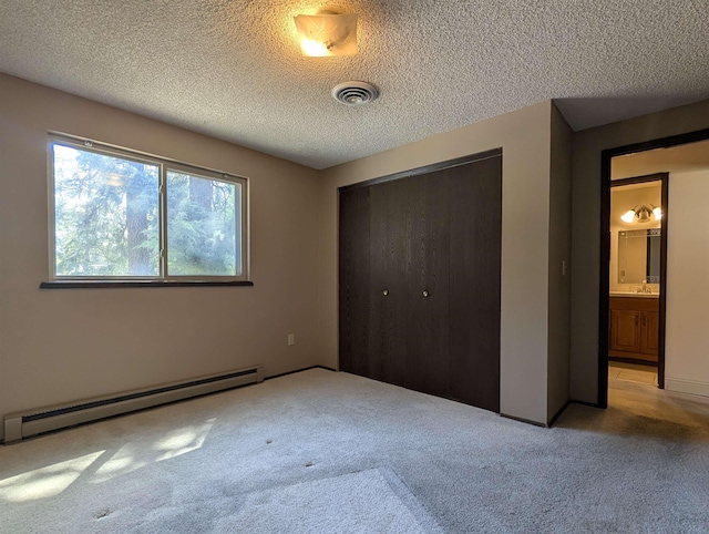 unfurnished bedroom featuring a baseboard radiator, carpet floors, a closet, a textured ceiling, and a sink