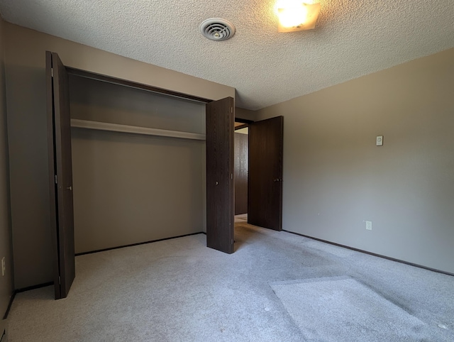 unfurnished bedroom with light colored carpet, a textured ceiling, and a closet
