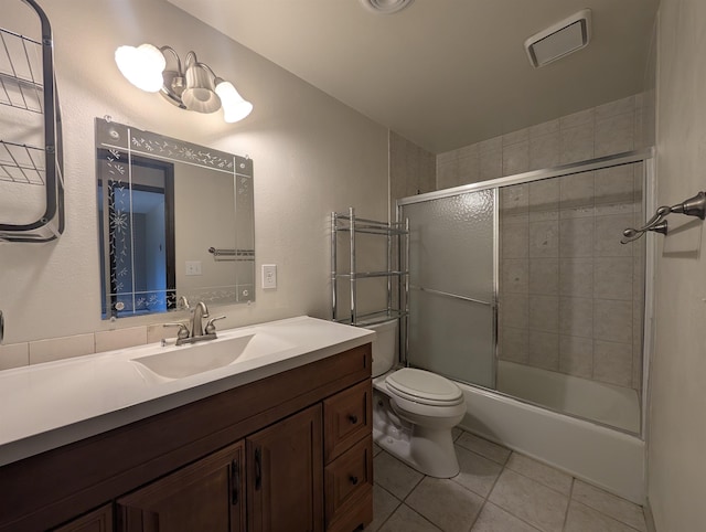 bathroom with tile patterned floors, vanity, toilet, and bath / shower combo with glass door