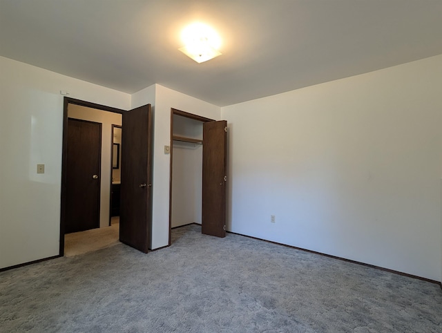 unfurnished bedroom with light carpet, a closet, and baseboards