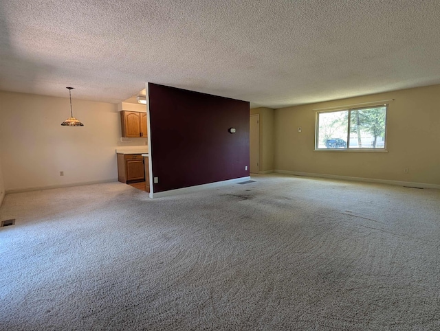 unfurnished living room with a textured ceiling, baseboards, and light carpet