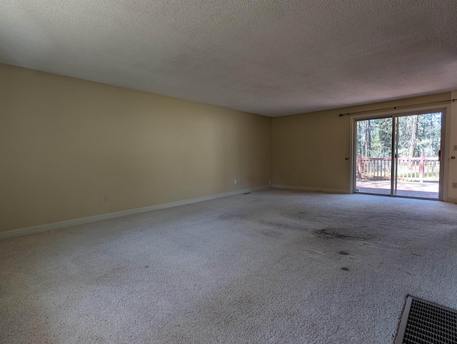 carpeted spare room featuring a textured ceiling and baseboards