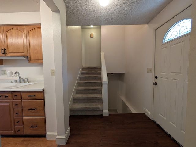 foyer featuring baseboards, stairs, a textured ceiling, and wood finished floors
