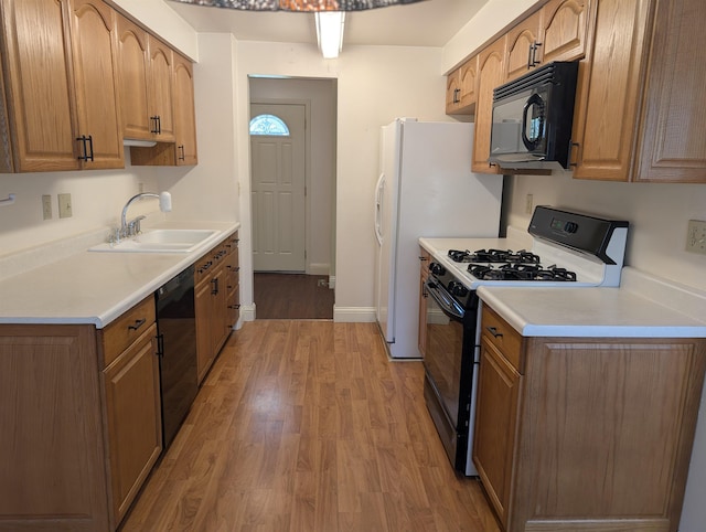 kitchen featuring black appliances, a sink, light wood-style flooring, light countertops, and brown cabinets
