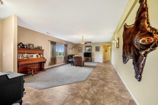 living room with light tile patterned floors, baseboards, light colored carpet, and a ceiling fan
