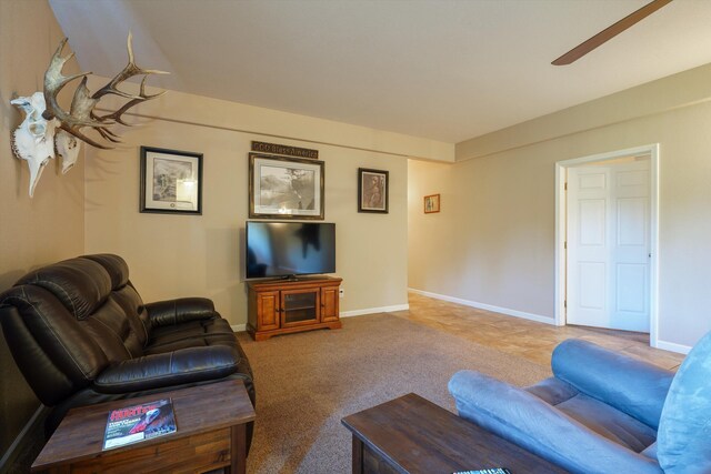 living room with ceiling fan, baseboards, and carpet
