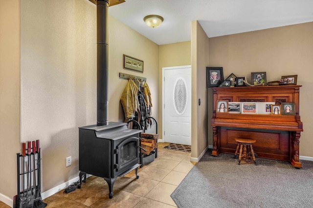 entrance foyer featuring a wood stove, baseboards, and tile patterned flooring