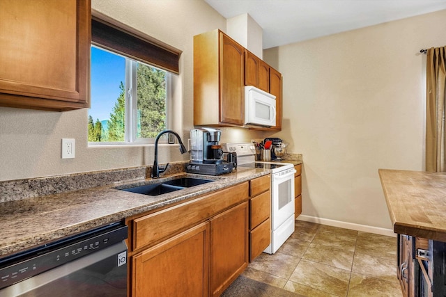 kitchen with white appliances, a sink, brown cabinets, and baseboards