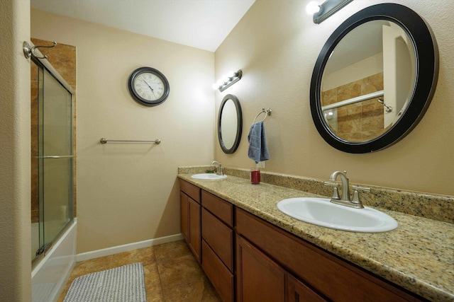 bathroom with double vanity, tile patterned flooring, baseboards, and bath / shower combo with glass door