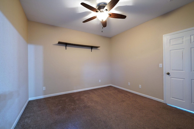 unfurnished room with a ceiling fan, dark colored carpet, and baseboards