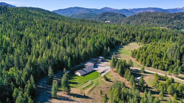aerial view of property and surrounding area featuring a heavily wooded area and mountains