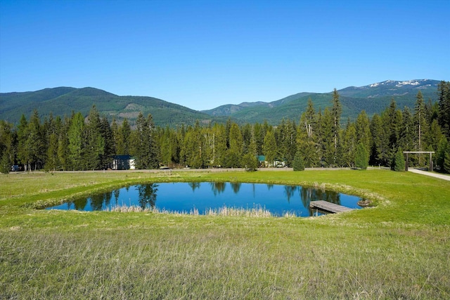 water view with a mountain backdrop and a heavily wooded area