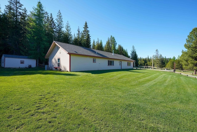 rear view of property featuring a lawn, an outbuilding, and central AC unit