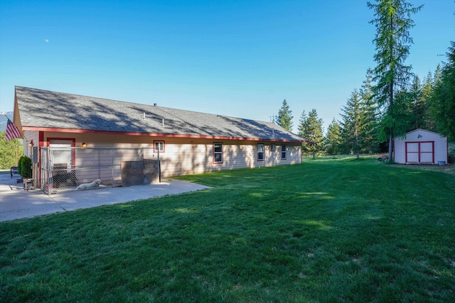 rear view of house with a storage shed, an outbuilding, a yard, and a patio area