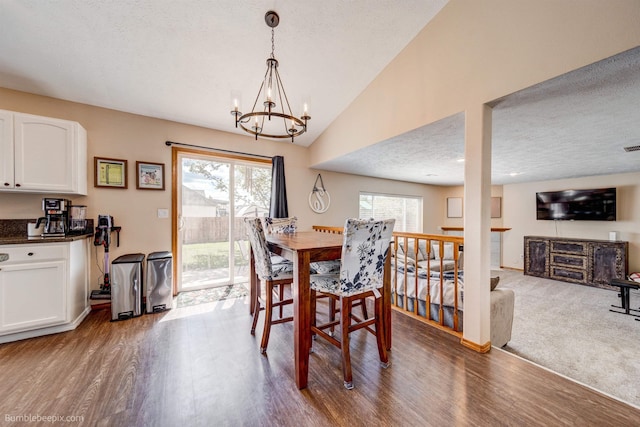 dining area with wood finished floors, a chandelier, a textured ceiling, and lofted ceiling