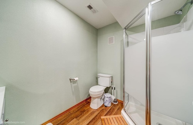 bathroom with a stall shower, wood finished floors, and toilet