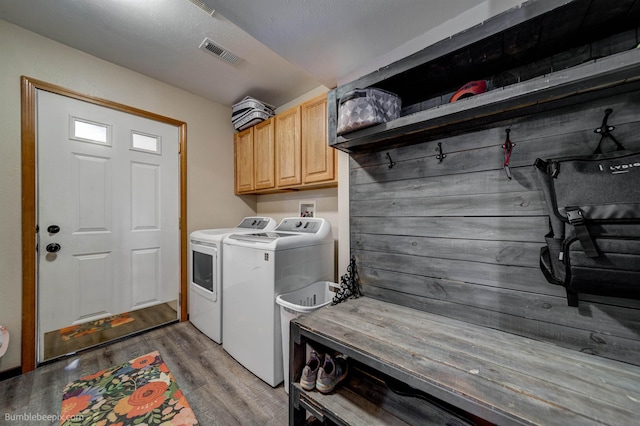 clothes washing area featuring cabinet space, washer and clothes dryer, and wood finished floors