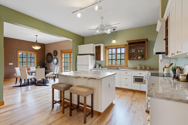 4408 E Spangle Creek Rd, Valleyford, WA 99036 - kitchen featuring freestanding refrigerator, light wood-style floors, stainless steel microwave, rail lighting, and white cabinets