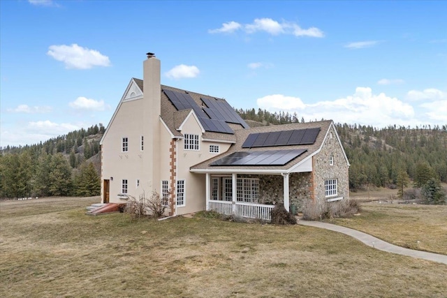 4408 E Spangle Creek Rd, Valleyford, WA 99036 - view of home's exterior with a yard, a chimney, stucco siding, solar panels, and a porch