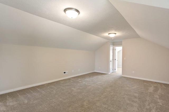 bonus room featuring carpet flooring, vaulted ceiling, a textured ceiling, and baseboards