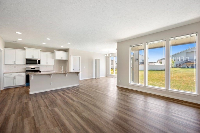 unfurnished living room featuring a textured ceiling, a chandelier, dark wood-style flooring, baseboards, and recessed lighting
