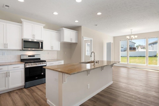 kitchen featuring appliances with stainless steel finishes, a sink, wood finished floors, white cabinets, and recessed lighting