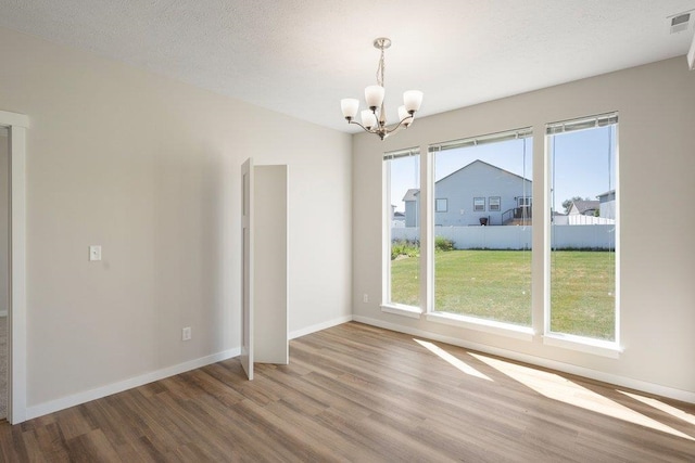 unfurnished dining area with a chandelier, wood finished floors, and baseboards