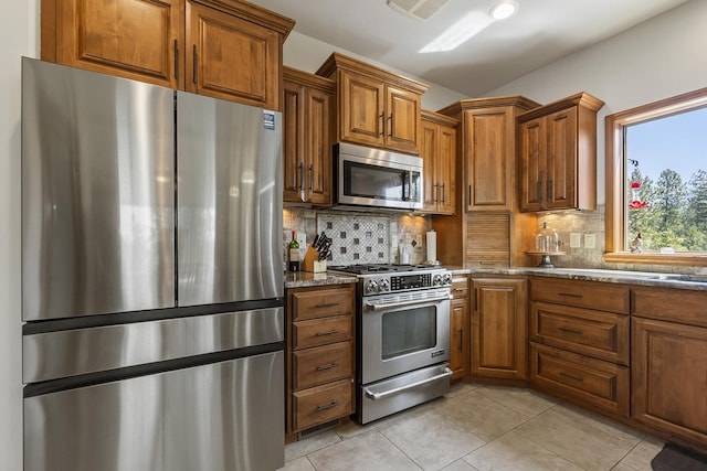 12715 E Deer Creek Rd, Chattaroy, WA 99003 - kitchen with appliances with stainless steel finishes, brown cabinetry, dark stone counters, and tasteful backsplash
