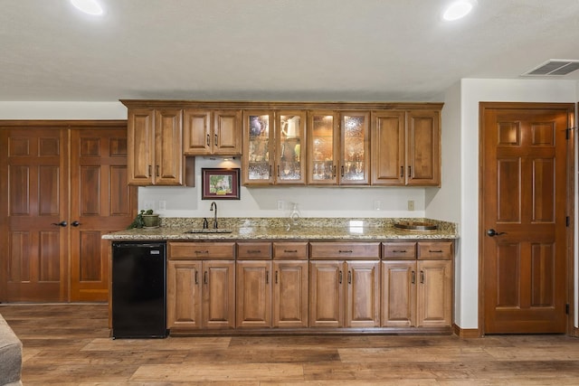 12715 E Deer Creek Rd, Chattaroy, WA 99003 - kitchen featuring a sink, brown cabinetry, light stone countertops, glass insert cabinets, and wood finished floors
