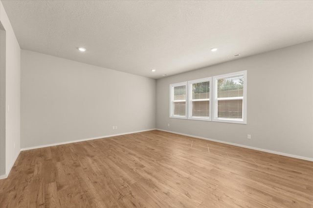 unfurnished room with light wood-style flooring, baseboards, recessed lighting, and a textured ceiling