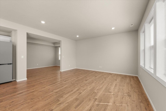 unfurnished living room with light wood-style floors, recessed lighting, and baseboards