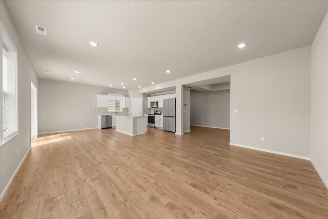 unfurnished living room with light wood finished floors, baseboards, and recessed lighting