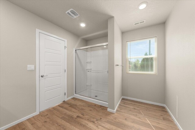 bathroom with a stall shower, wood finished floors, baseboards, and recessed lighting
