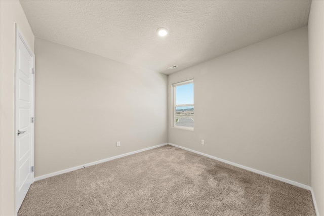 unfurnished room featuring carpet, baseboards, and a textured ceiling