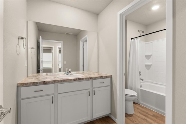 bathroom with wood finished floors, toilet, vanity, and shower / bath combination with curtain