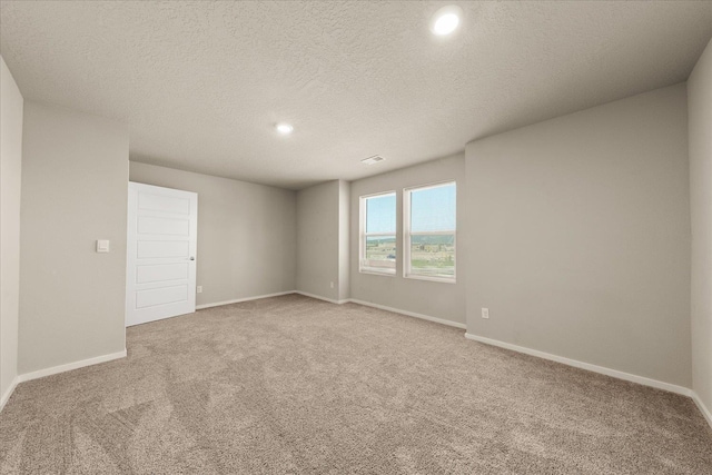 spare room featuring light colored carpet, recessed lighting, baseboards, and a textured ceiling