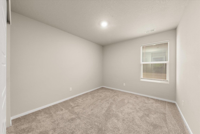spare room featuring carpet flooring, baseboards, and a textured ceiling