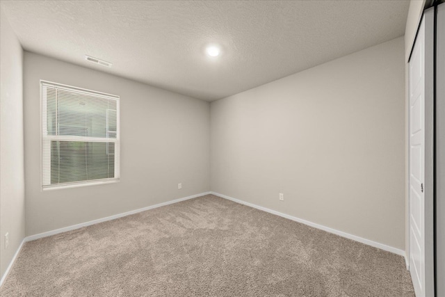 spare room featuring carpet, baseboards, and a textured ceiling
