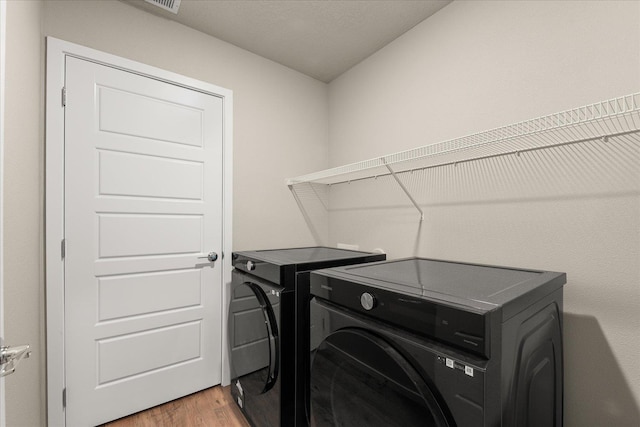 washroom with washer and clothes dryer and light wood-type flooring