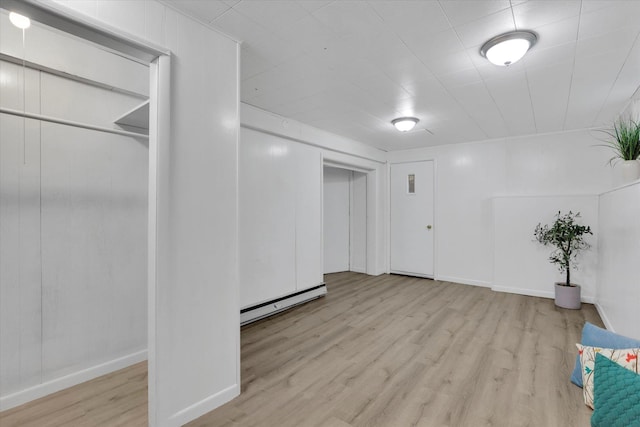 below grade area featuring a baseboard heating unit, wood finished floors, and baseboards