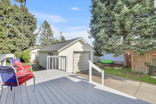 deck with an outdoor structure, a detached garage, and fence