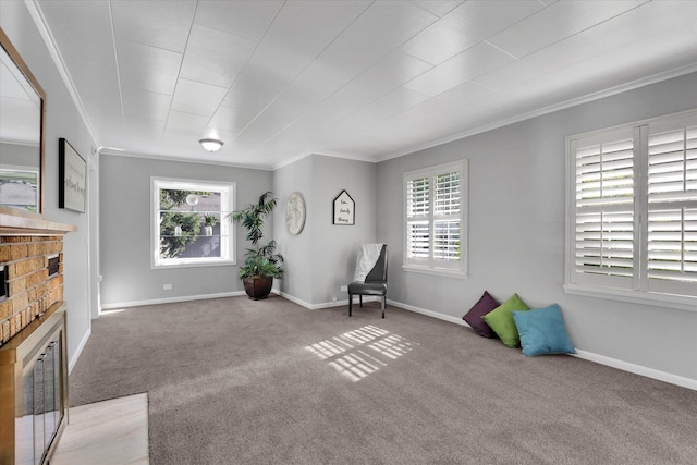 sitting room with crown molding, carpet floors, healthy amount of natural light, a brick fireplace, and baseboards