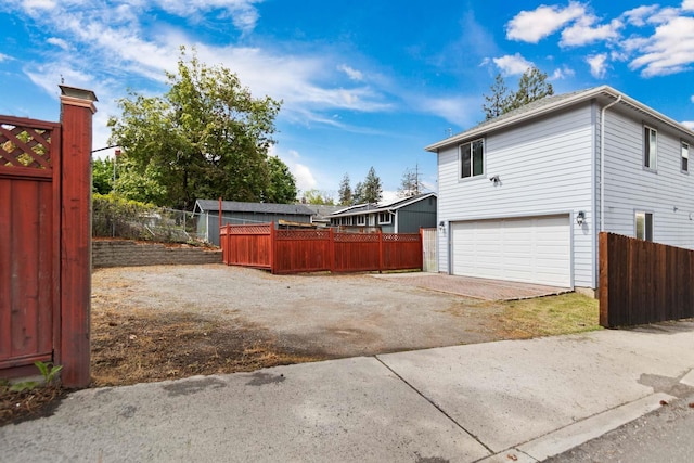 view of property exterior with an attached garage, fence, and driveway