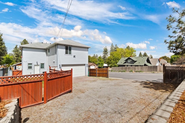 back of house featuring driveway, an attached garage, and fence